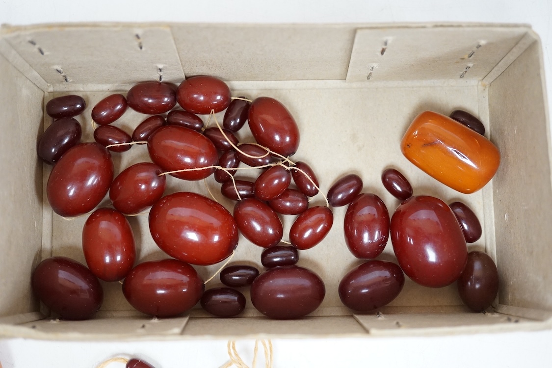 A single strand amber bead necklace, with filigree metal spacers, 48cm, gross 84 grams, together with a group of loose graduated simulated cherry amber beads, gross weight 117 grams.